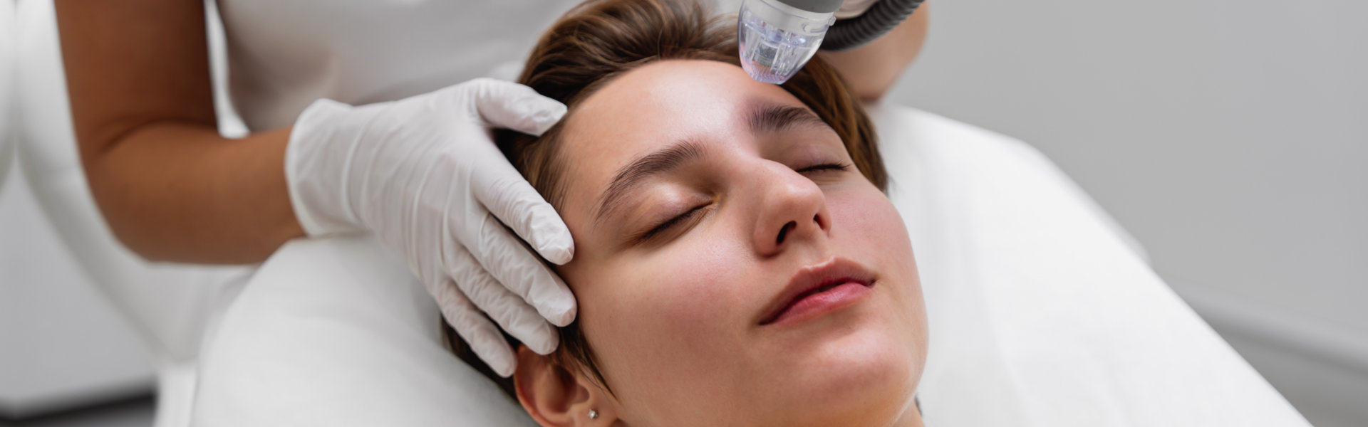 cosmetologist microneedling a woman's face