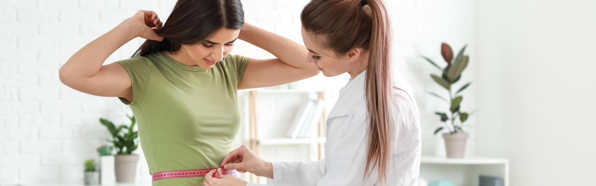 Nutritionist measuring waist of young woman